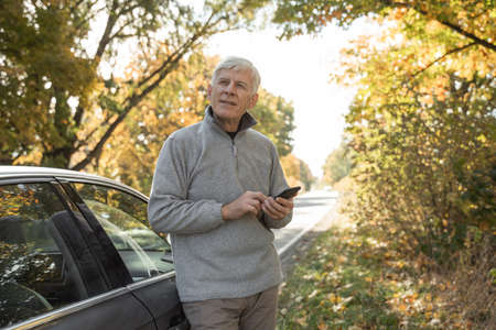 Man looking away with pensive expression while standing near his car at the forestの写真素材