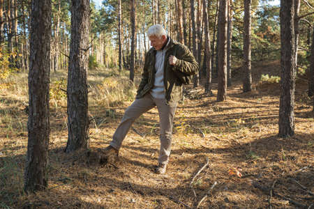 Man going through the lonely forest and looking at the ground while enjoying