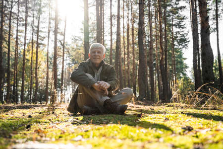 Senior man sitting at the lotus pose and warming at the sun raysの写真素材