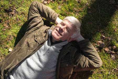 Male person laying at the grass and smiling while feeling calm and peacefulの写真素材