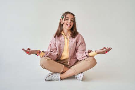 Happy caucasian girl sitting in lotus position at the floor at the studioの写真素材