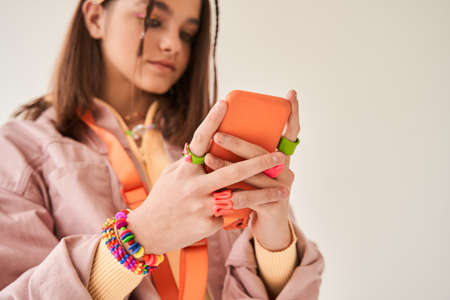 Cute girl in bright look holding her smartphone in vivid case while posingの写真素材