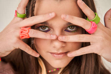 Cherry girl with brunette hair looking at the camera through her fingers while posingの写真素材