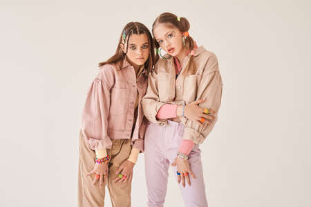 Two besties wearing stylish clothes posing at the studio over the light beige backgroundの写真素材