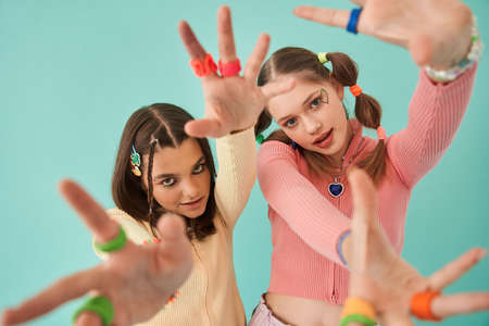Girls stretching hands to the camera while posing at bright and creative clothesの写真素材