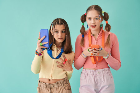 Girl looking at the cell phone and making selfie while standing hear her friendの写真素材