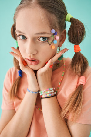 Serious teen girl keeping her hands near her face while standing and posingの写真素材