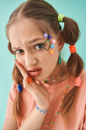Teen girl wearing creative and bright look sitting at the studio and looking at the cameraの写真素材