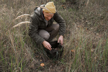Mushroom picker with a large bag looking for mushrooms while collectingの写真素材