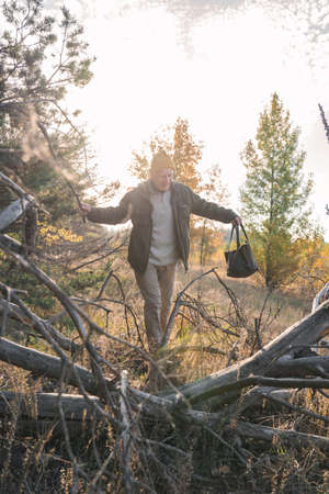 Full length view of the mature man sneaking through the sticks at the forest and picking mushrooms...