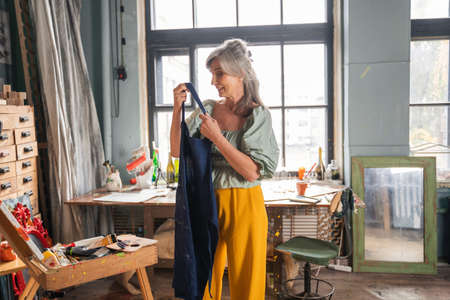 Senior woman taking on her apron while preparing to the drawing at her art studioの写真素材