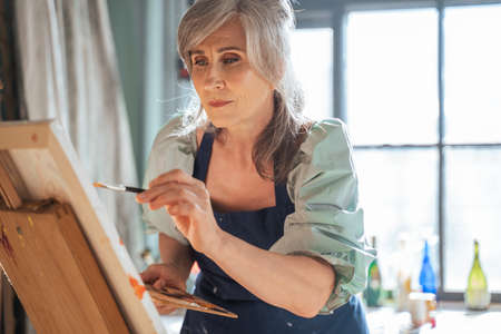 Mature female artist expressing her thoughts and feeling through paintingの写真素材