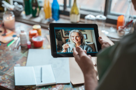Woman chatting with her female friend via video call at the tablet computerの写真素材