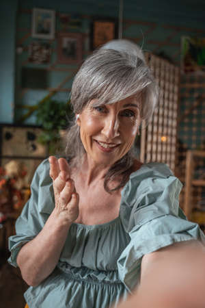 Woman holding her device and gesturing while chatting with somebody