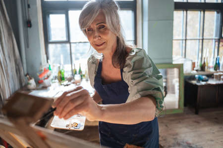 Talented senior female artist preparing for a contest while drawing at the canvasの写真素材