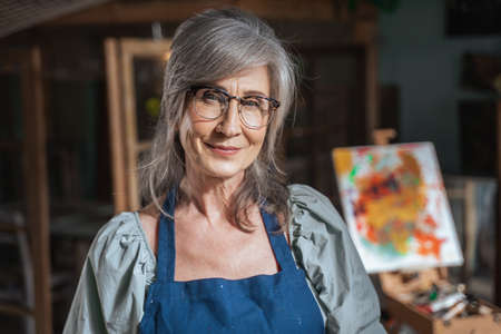 Female artist wearing glasses for vision looking at the camera with pleasure smile
