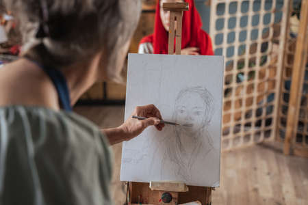 Professional mature artist drawing portrait of her modelの写真素材