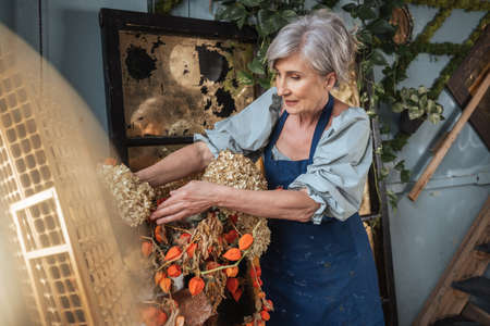 Woman standing near the bouquet of the dry flowers while preparing drawing still lifeの写真素材