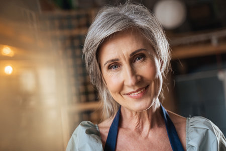 Senior female painter in apron looking at the camera with pleasure smileの写真素材