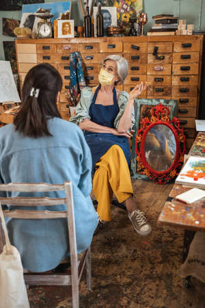 Retirement woman artist wearing protective mask holding drawing lesson for one student girlの写真素材