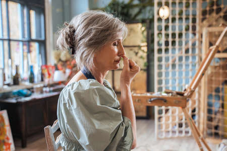 Senior lady keeping her eyes closed and doing breathing exerciseの写真素材