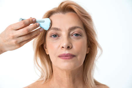 Retirement woman receiving a non-surgical rejuvenation procedureの写真素材