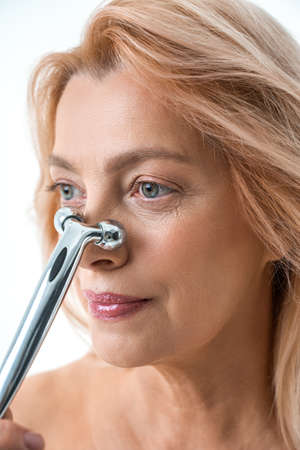 Beautiful woman massaging her nose against white color backgroundの写真素材