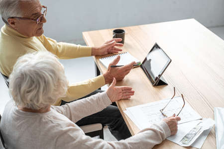 Mature couple with financial documents and utility bills at table in home interiorの写真素材