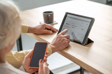 Elderly male person scrolling special medicine app while spending time together with wifeの写真素材