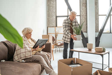 Concentrated man unpacking boxes in living room