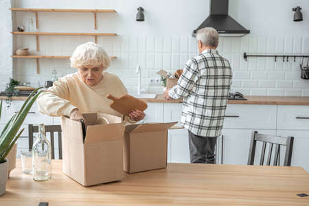 Happy elderly couple unpacking carton boxes in their new houseの写真素材