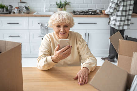 Senior woman holding smartphone and having video call with relativesの写真素材
