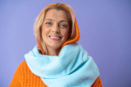 Elderly woman dressed in warm knitted clothes smiling broadly and being in happy moodの写真素材