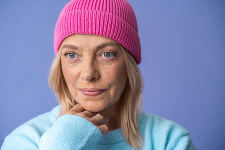 Serious woman wearing hat looking away with calm expression while posing