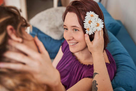 women looking at her girlfriend while she tucks flowers behind her earの写真素材