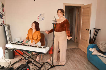 Good looking young female signing a lyric song while standing in front of microphoneの写真素材