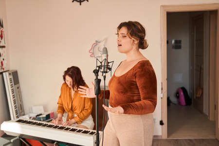 Teenage caucasian girl influencer playing piano music while her girlfriendの写真素材