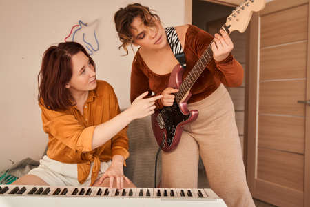 Woman looking at the guitar and telling something to her girlfriend while discussingの写真素材