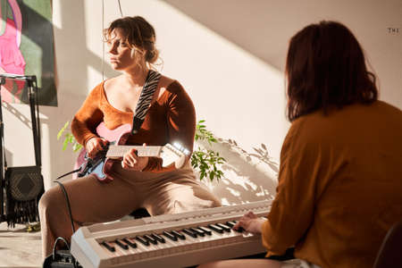 Woman songwriter playing lyrics song at the piano at her living roomの写真素材