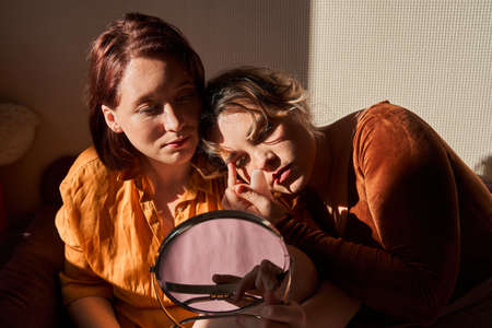 Girls bonding to each other and looking at the mirrorの写真素材