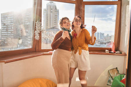 Couple in party accessorizes holding sparklers and bonding to each otherの写真素材