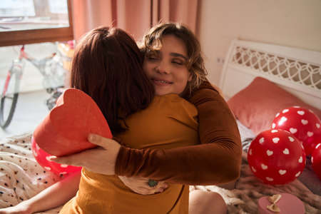 Grateful women embracing her girlfriend while feeling happy after getting present