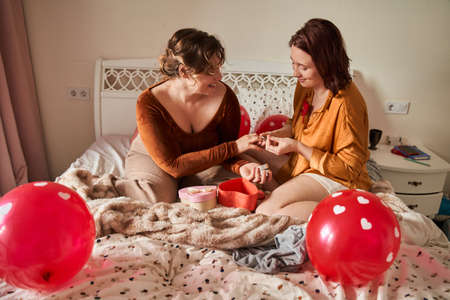 Women loves her girlfriend and making offer to her while giving a ring at homeの写真素材