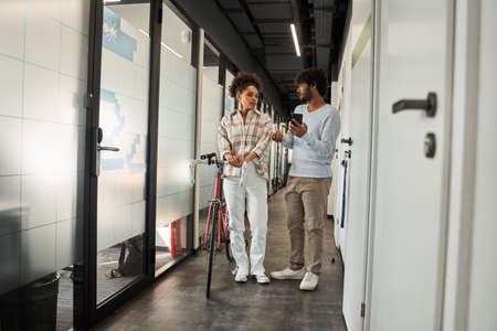 Multiracial coworkers going through the hall together with bicycleの写真素材