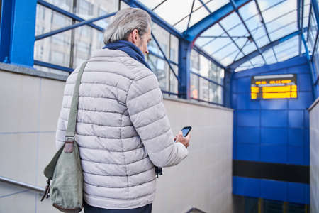 Pensioner gentleman reading message on smartphone or using special appの写真素材