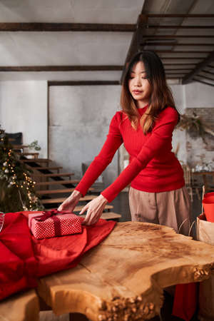 Asian woman putting at the table gift box wrapped at the red paperの写真素材