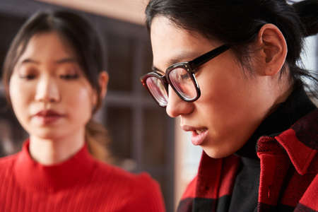 Concentrated asian man talking with his girlfriend while spending time at their apartments
