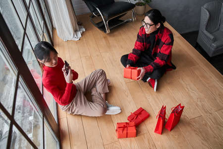 Asian couple in love sitting at the floor around the presents
