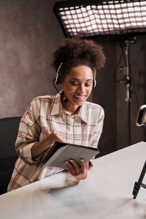 Woman sitting at the studio and looking at the tablet with pleasure smile