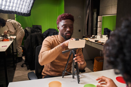Stylish guy correcting smartphone at the tripod while preparing recording video